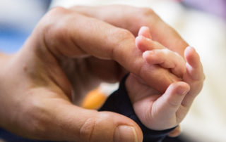 Hand eines Kleinkindes umfasst Finger einer Erwachsenenhand